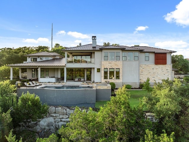 821 Laughing Dog Ct, Leander, TX 78641 - rear view of property with a standing seam roof, a metal roof, a patio area, a chimney, and stone siding