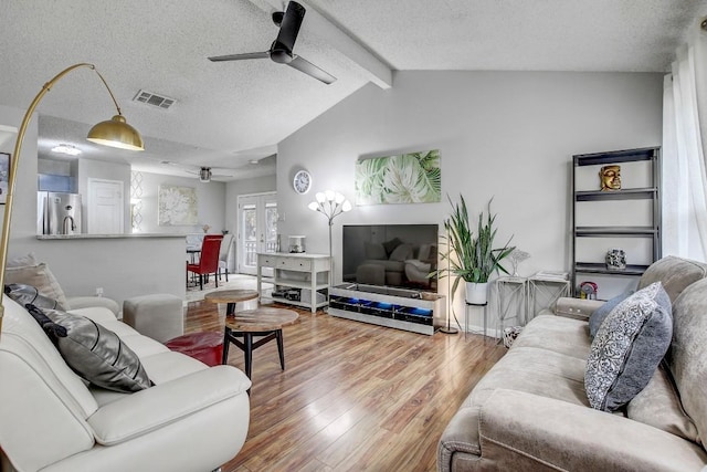 living room with hardwood / wood-style floors, a textured ceiling, vaulted ceiling with beams, and ceiling fan