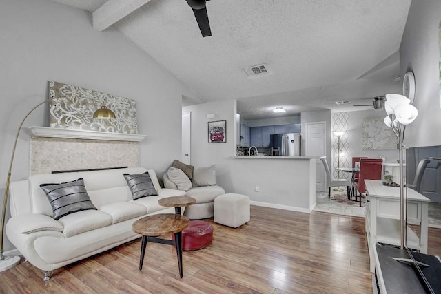 living room featuring hardwood / wood-style flooring, vaulted ceiling with beams, a textured ceiling, and ceiling fan