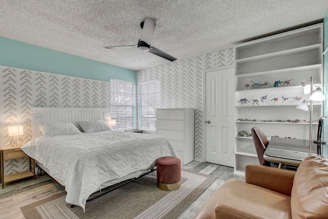 bedroom featuring ceiling fan, light hardwood / wood-style flooring, and a textured ceiling