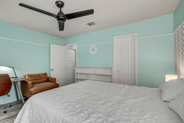 bedroom featuring ceiling fan, wood-type flooring, and a textured ceiling