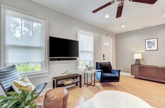 living room with plenty of natural light, ceiling fan, and light wood-type flooring