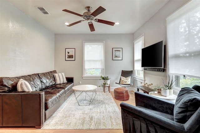 living room with ceiling fan, plenty of natural light, and light wood-type flooring