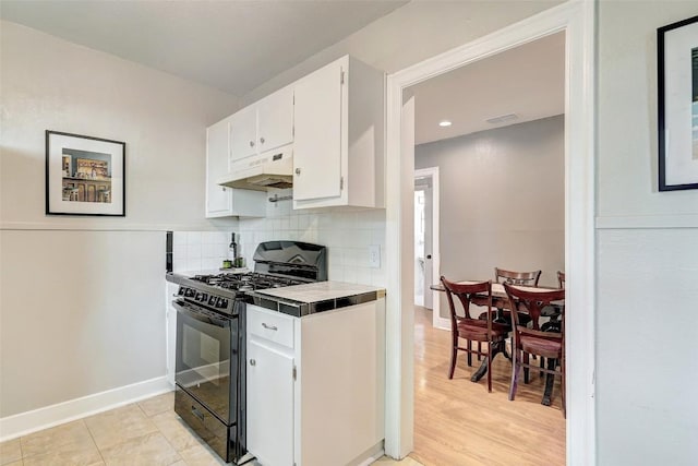 kitchen featuring light hardwood / wood-style flooring, tasteful backsplash, white cabinets, black range with gas stovetop, and tile countertops