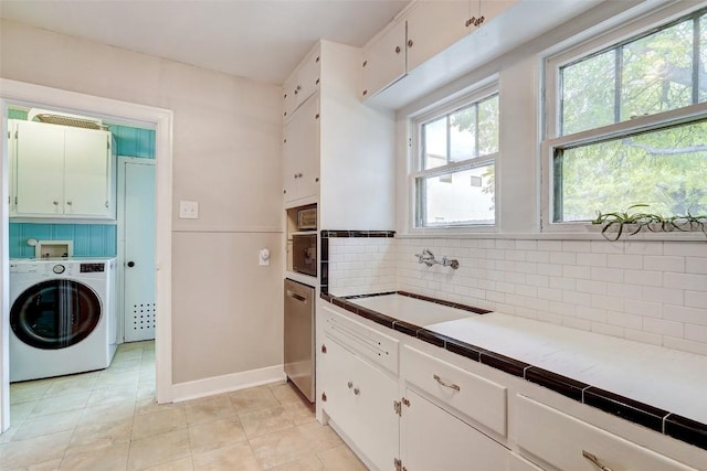 kitchen with washer / dryer, sink, tasteful backsplash, tile countertops, and white cabinets