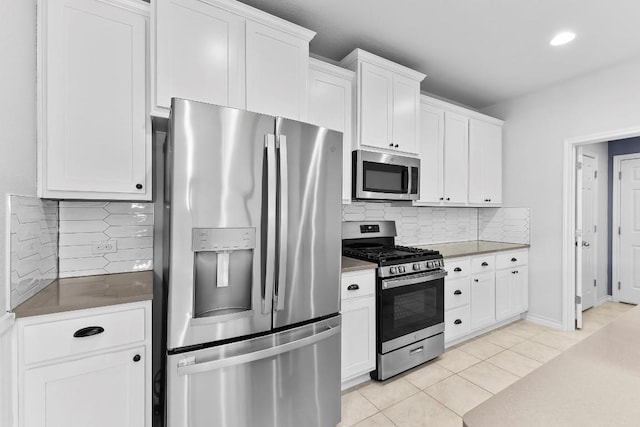 kitchen with decorative backsplash, appliances with stainless steel finishes, light tile patterned flooring, and white cabinetry