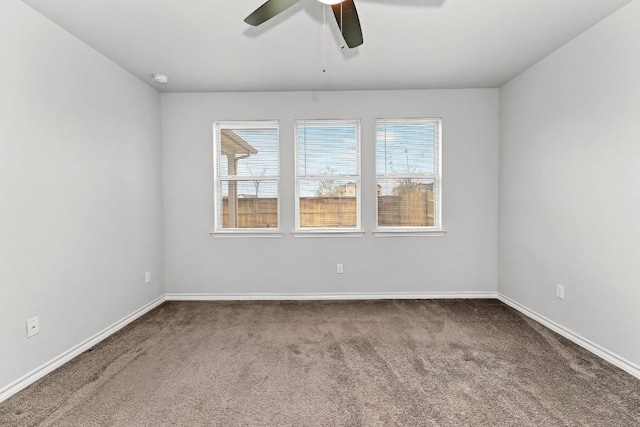 carpeted empty room featuring baseboards, a wealth of natural light, and ceiling fan