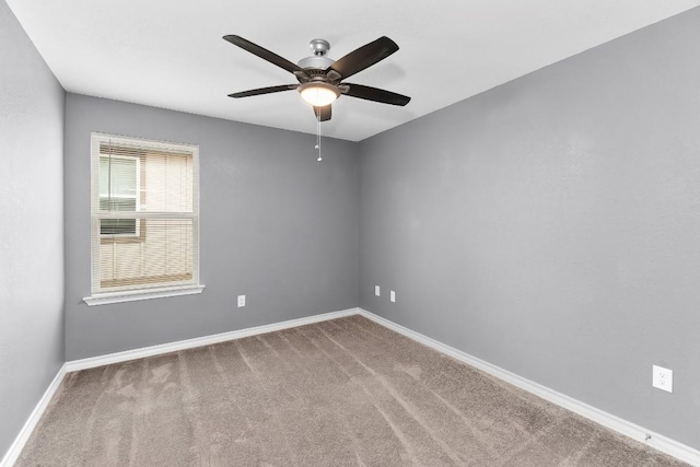 carpeted empty room featuring a ceiling fan and baseboards