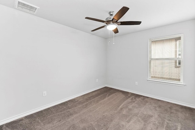 empty room with a ceiling fan, baseboards, visible vents, and dark carpet