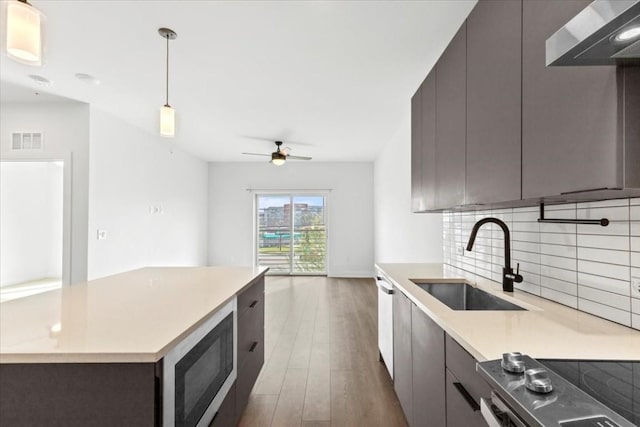 kitchen featuring built in microwave, sink, electric range, pendant lighting, and backsplash