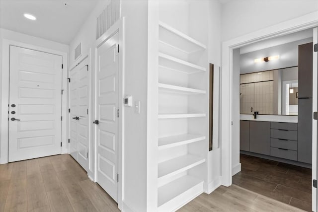 hall featuring light hardwood / wood-style floors and built in shelves