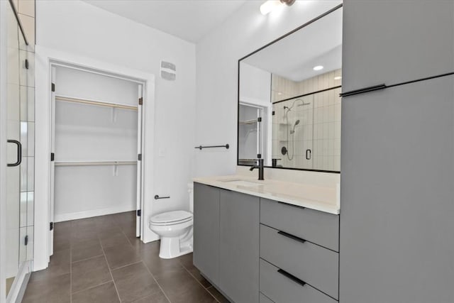 bathroom featuring vanity, toilet, a shower with shower door, and tile patterned flooring