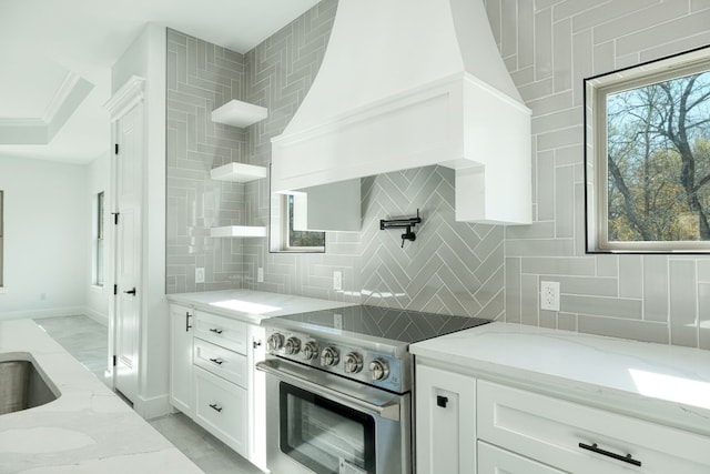 kitchen featuring light stone counters, stainless steel electric range, and white cabinets