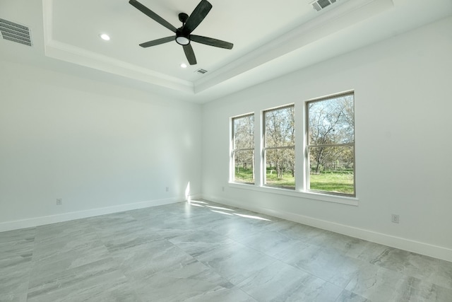 spare room with ceiling fan and a raised ceiling