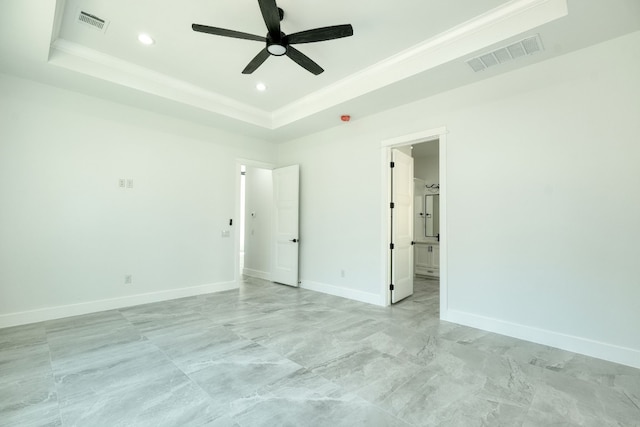 unfurnished bedroom featuring crown molding, ensuite bath, a tray ceiling, and ceiling fan