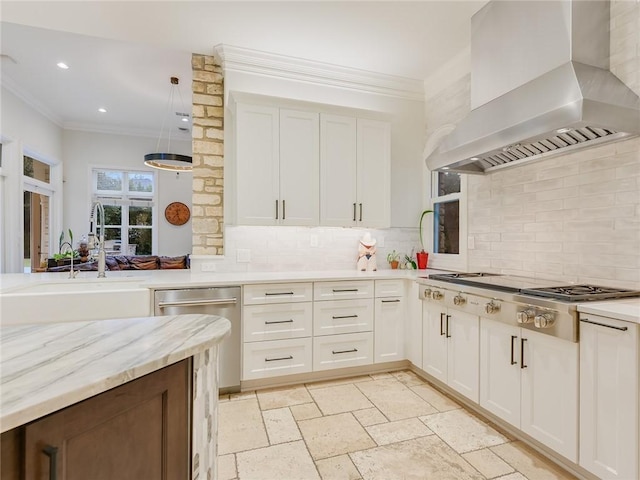 kitchen featuring crown molding, appliances with stainless steel finishes, white cabinetry, range hood, and decorative light fixtures