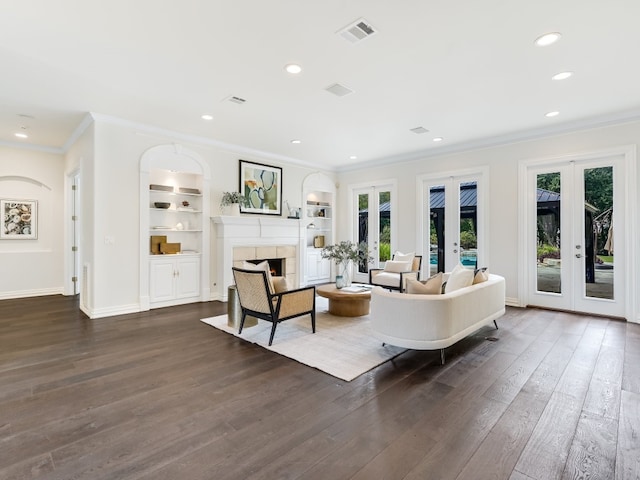 living room with french doors, crown molding, dark hardwood / wood-style floors, built in features, and a fireplace