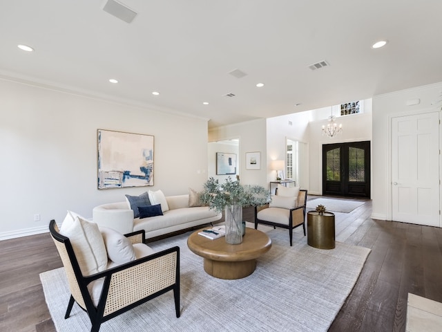 living room with hardwood / wood-style floors, crown molding, a notable chandelier, and french doors