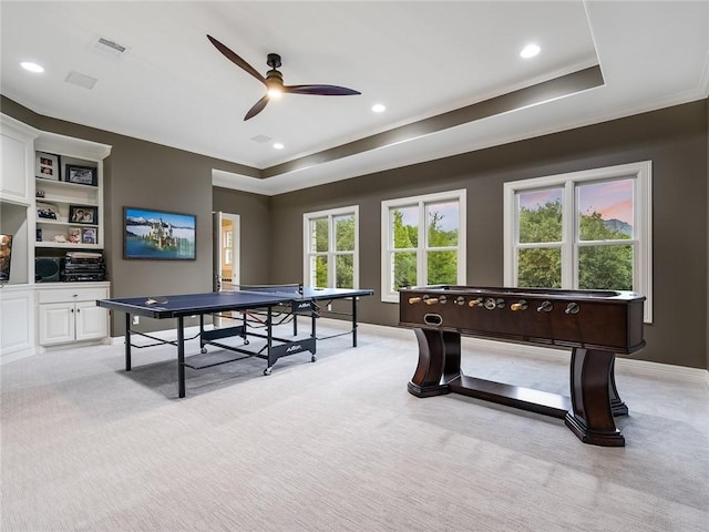 rec room with light carpet, a tray ceiling, and ceiling fan