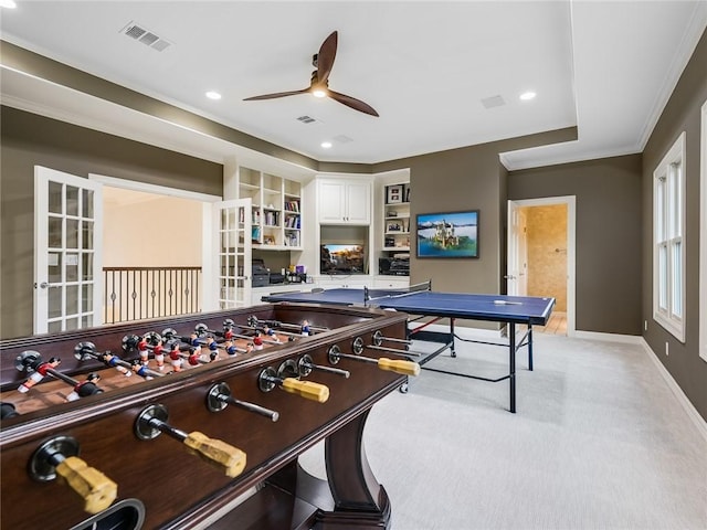 rec room with crown molding, ceiling fan, built in shelves, and light colored carpet