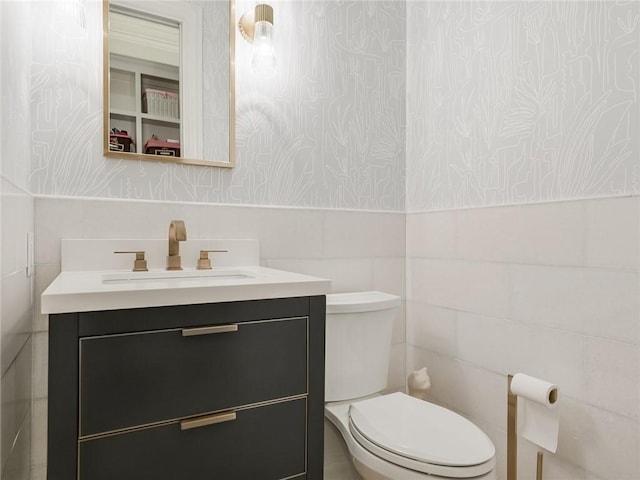 bathroom featuring vanity, toilet, and tile walls