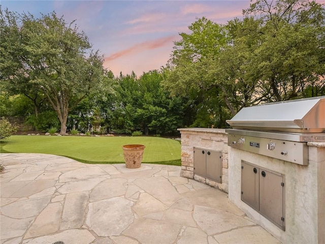 patio terrace at dusk featuring area for grilling and a yard