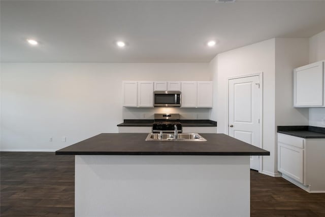 kitchen with stainless steel appliances, a sink, white cabinets, dark countertops, and dark wood finished floors