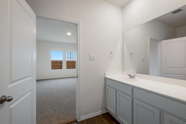 bathroom featuring visible vents, vanity, baseboards, and wood finished floors