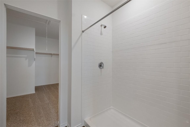 full bath with a walk in closet, a shower stall, and baseboards