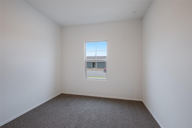 unfurnished room with dark carpet and baseboards