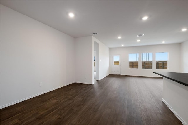 unfurnished living room with recessed lighting, visible vents, dark wood finished floors, and baseboards