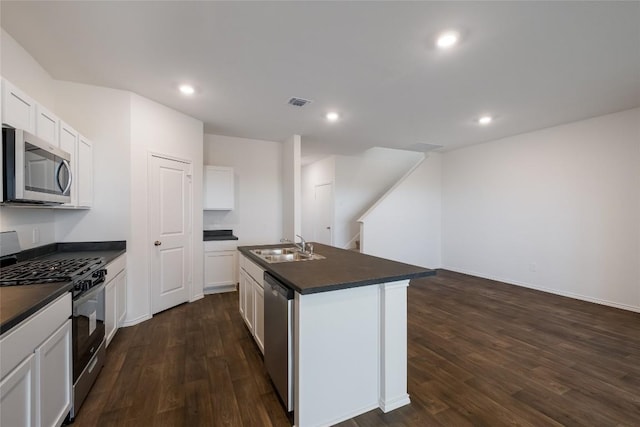 kitchen with appliances with stainless steel finishes, dark countertops, dark wood-type flooring, and a sink