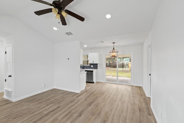 unfurnished living room featuring lofted ceiling, ceiling fan with notable chandelier, and light hardwood / wood-style flooring