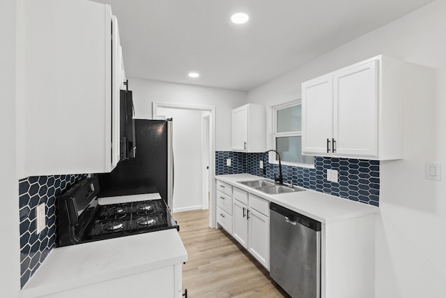 kitchen with tasteful backsplash, dishwasher, sink, white cabinets, and black gas stove