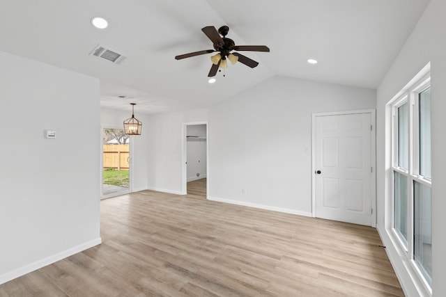 unfurnished room with ceiling fan with notable chandelier, vaulted ceiling, and light wood-type flooring