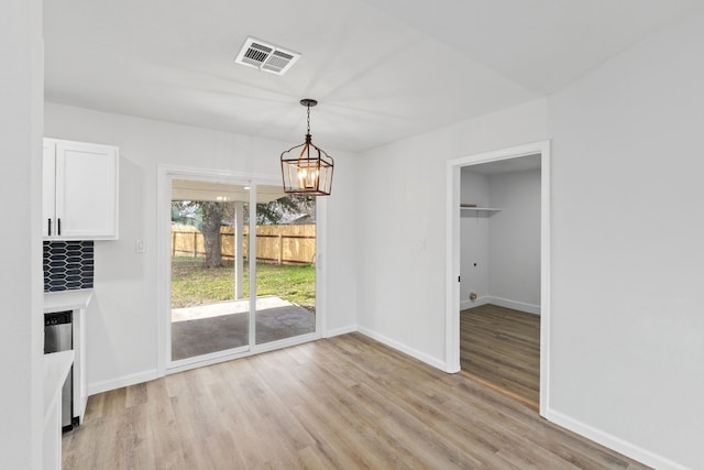 unfurnished dining area featuring a chandelier and light hardwood / wood-style floors