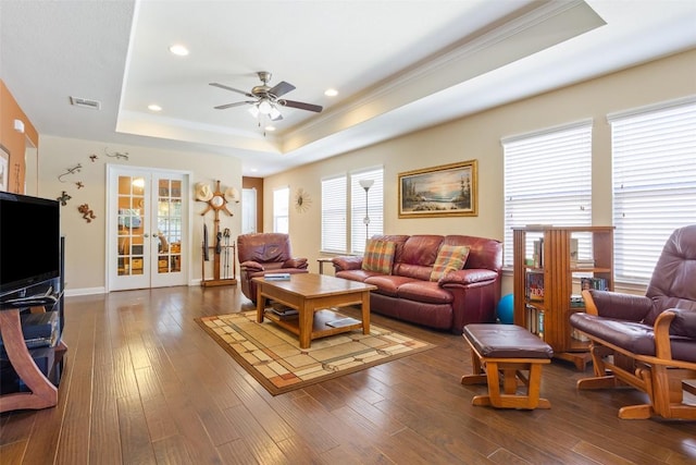 living room with a tray ceiling, dark hardwood / wood-style floors, french doors, and ceiling fan