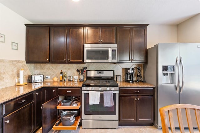 kitchen featuring light stone counters, dark brown cabinetry, appliances with stainless steel finishes, and tasteful backsplash