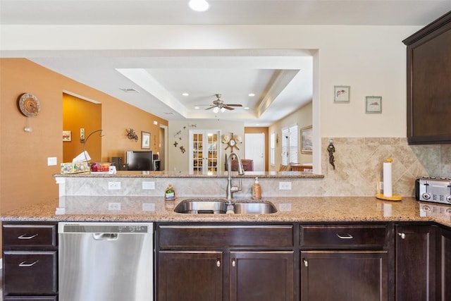 kitchen with dishwasher, sink, light stone counters, a raised ceiling, and dark brown cabinets