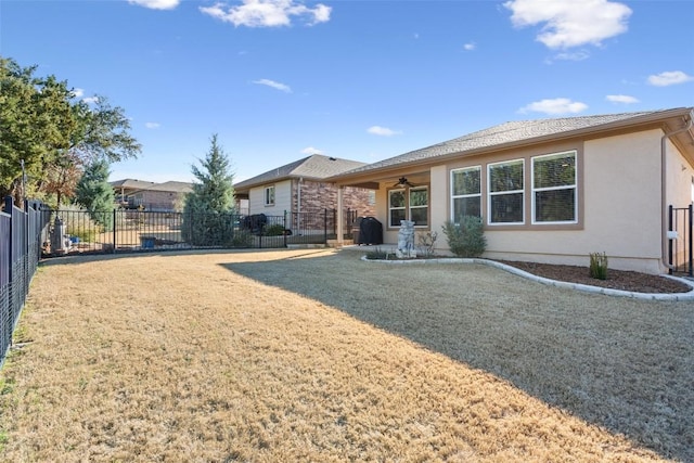 rear view of house with ceiling fan and a lawn