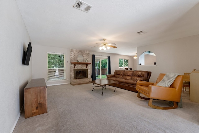 living room with a brick fireplace, light carpet, and ceiling fan