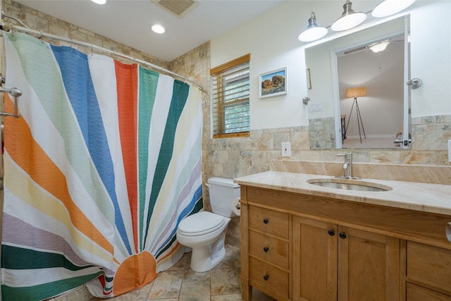 bathroom featuring vanity, toilet, and tile walls