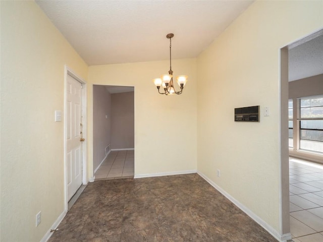 tiled spare room with a chandelier