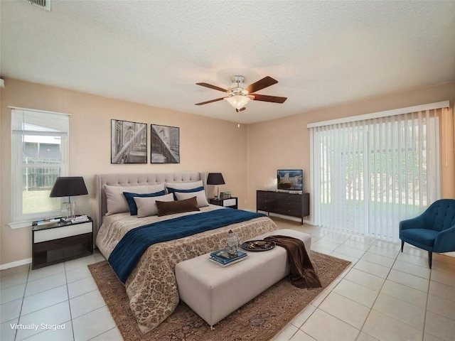 tiled bedroom with ceiling fan, access to exterior, multiple windows, and a textured ceiling