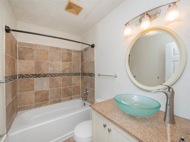 full bathroom with vanity, tiled shower / bath, a textured ceiling, and toilet