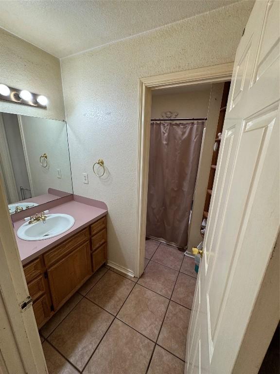 bathroom featuring a textured wall, curtained shower, tile patterned flooring, a textured ceiling, and vanity