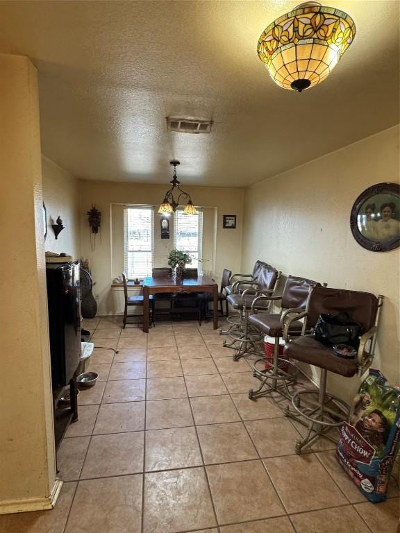 dining area featuring a textured ceiling, light tile patterned flooring, and visible vents