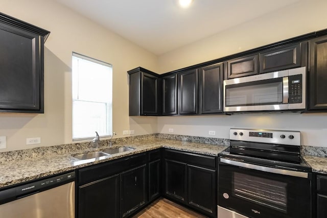 kitchen featuring sink, stainless steel appliances, light hardwood / wood-style floors, and light stone countertops