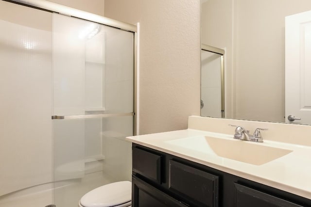 bathroom with walk in shower, vanity, and toilet