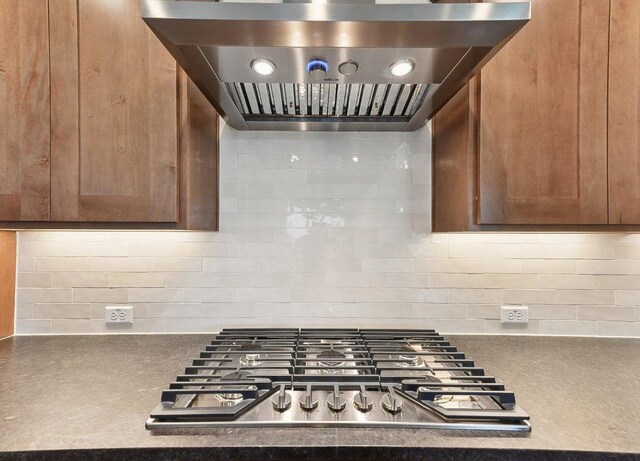 232 Flora Springs Cv, Liberty Hill, TX 78642 - kitchen featuring decorative backsplash, range hood, stainless steel gas stovetop, and dark countertops